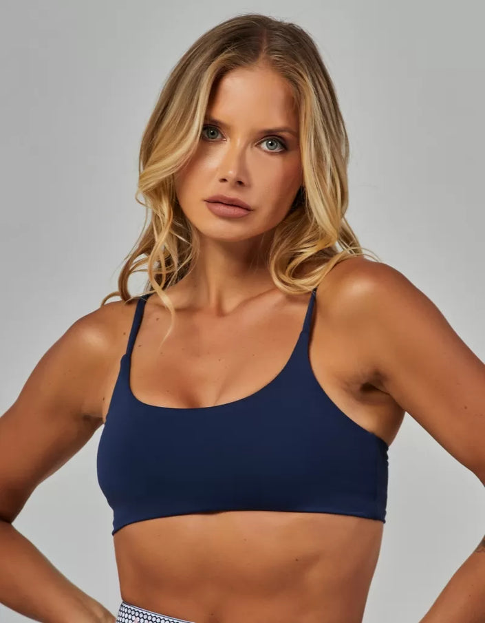 Woman wearing a navy blue sports bra against a gray background
